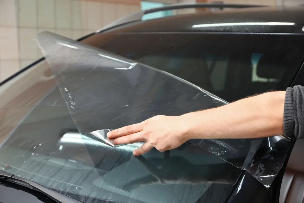 window tint being applied to windshield with scraper