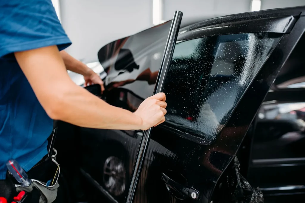dark window tint being applied to window on black car